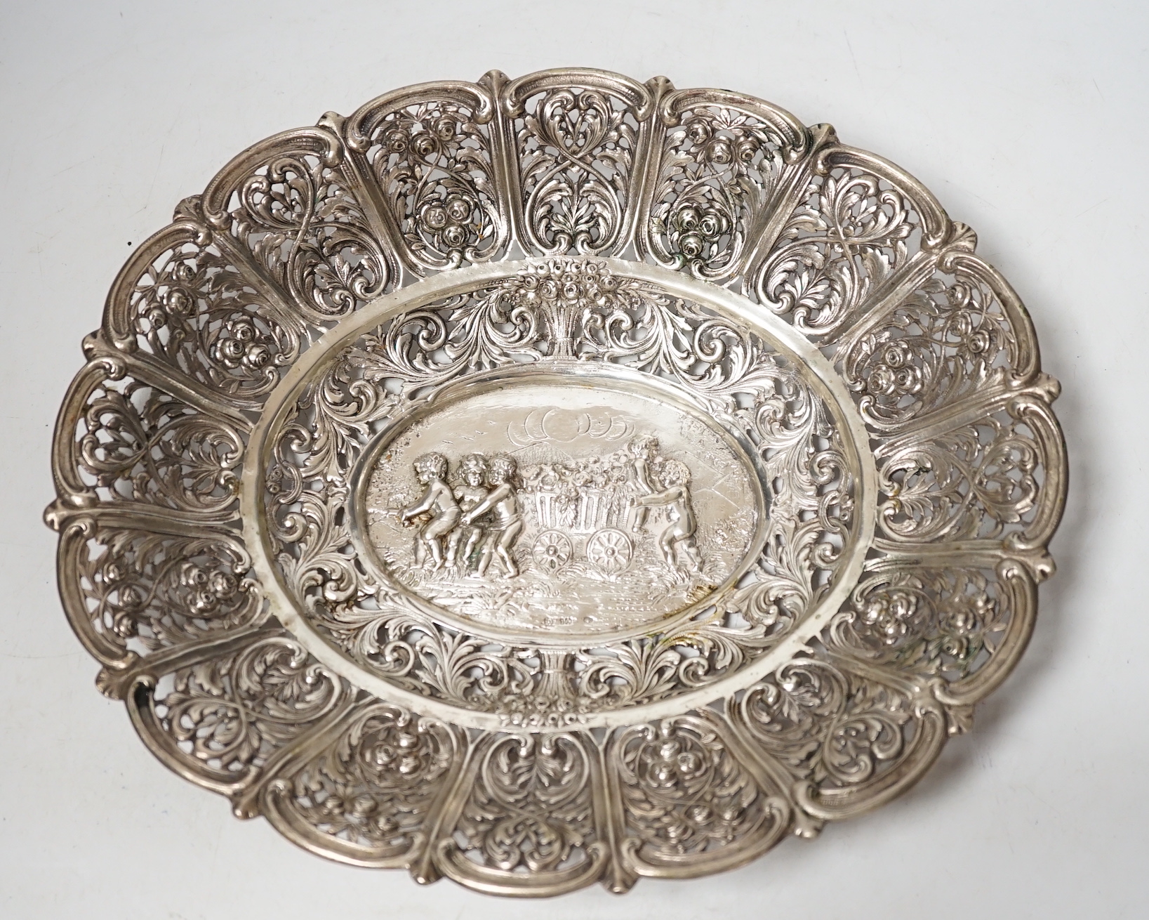 An early 20th century German 800 standard pierced white metal oval dish, decorated with putti and cart of flowers, 29.7cm, 13.2oz.